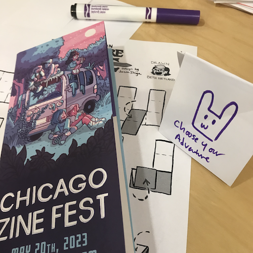 photograph of a mini choose-your-own-adventure zine, the Chicago Zine Fest program, and a purple marker on a table