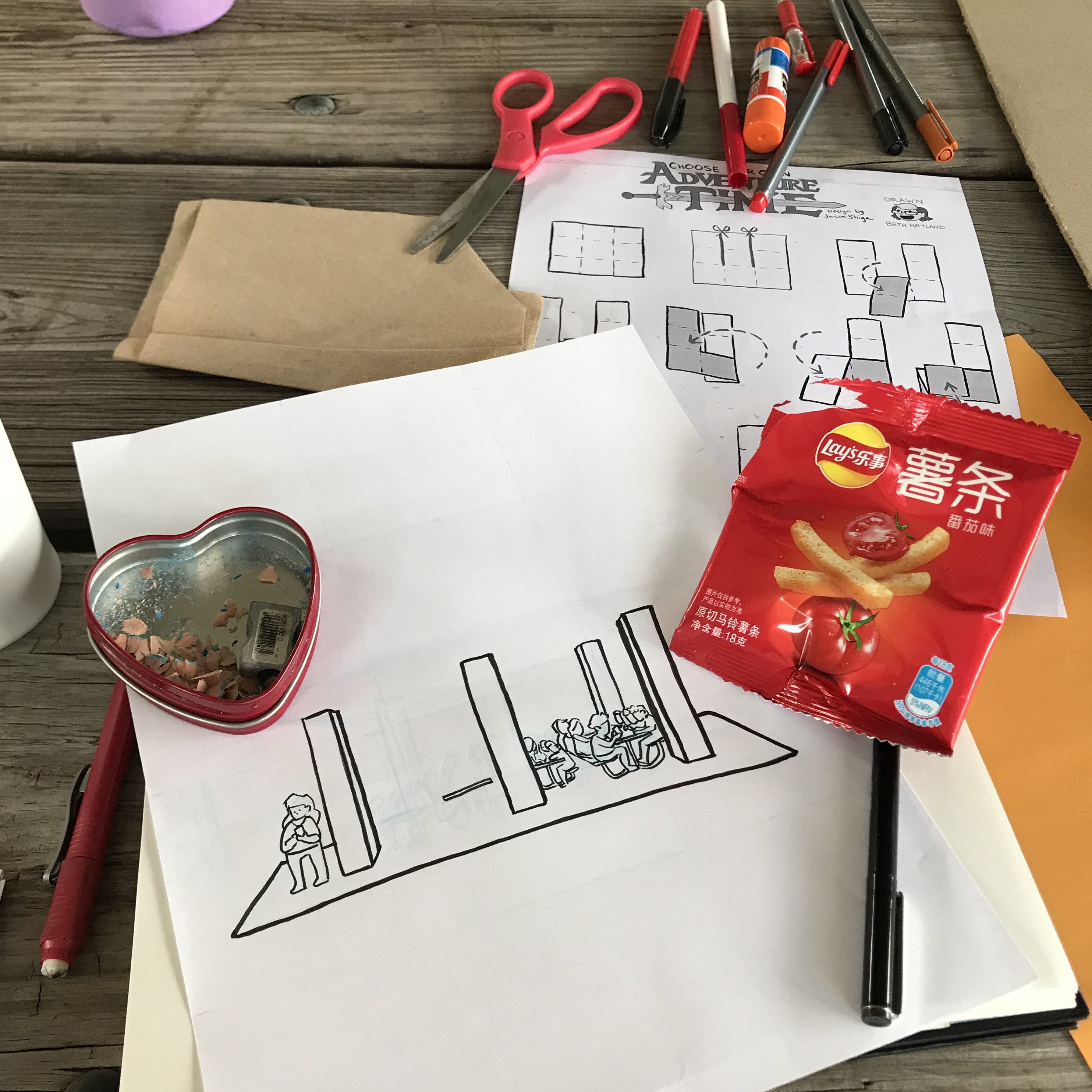 photograph of zine supplies and snack bags on a wooden picnic table