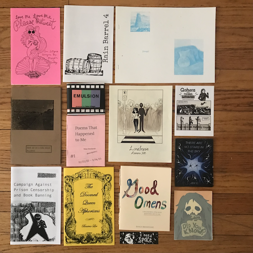 photograph of 1/2 Alex's CZF haul on a hardwood floor including mini zines, stickers, and prints