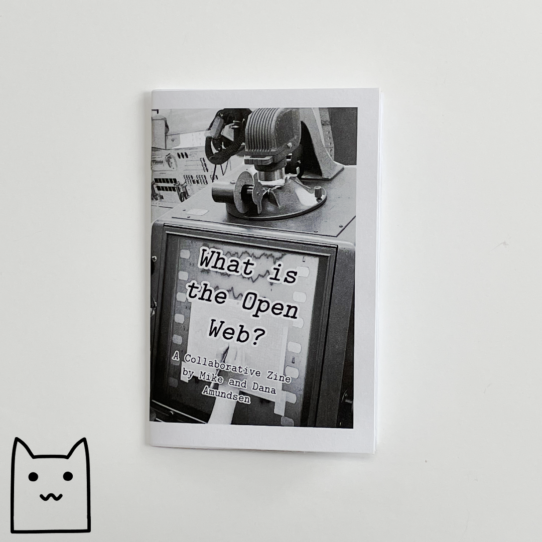 A photo of the cover of 'What is The Open Web?' featuring a hand reaching to write on a retro computer monitor.